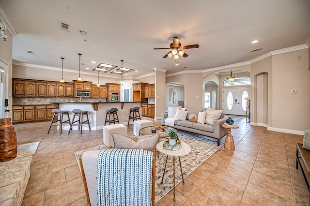 tiled living room with french doors, ceiling fan, and ornamental molding