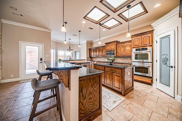 kitchen featuring a kitchen island with sink, stainless steel appliances, a breakfast bar, decorative light fixtures, and tasteful backsplash