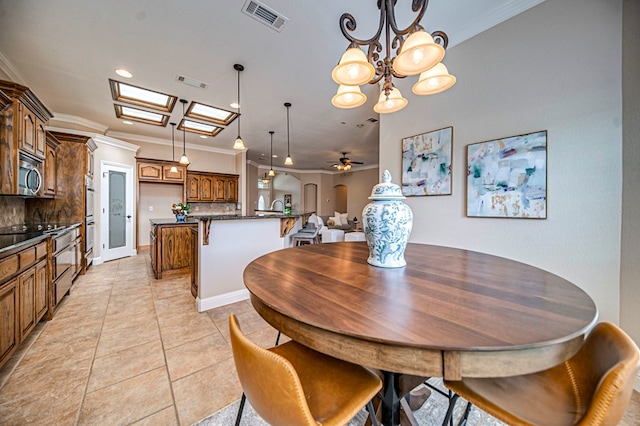 tiled dining room with ceiling fan with notable chandelier and crown molding