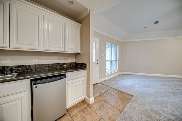 kitchen featuring dishwashing machine, crown molding, white cabinetry, dark stone counters, and light carpet