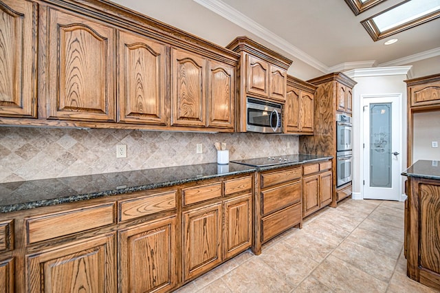 kitchen featuring dark stone countertops, a skylight, backsplash, appliances with stainless steel finishes, and ornamental molding