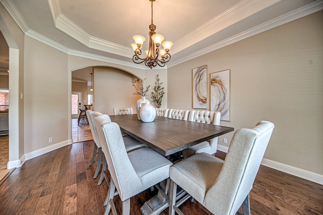 dining space with a chandelier, a tray ceiling, ornamental molding, and dark wood-type flooring