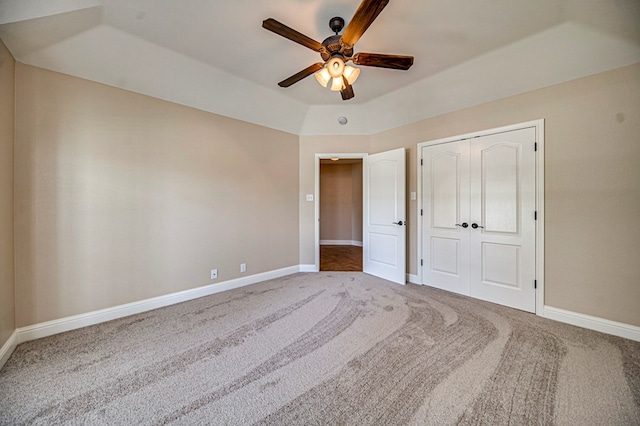 unfurnished bedroom with carpet, a closet, ceiling fan, and a tray ceiling