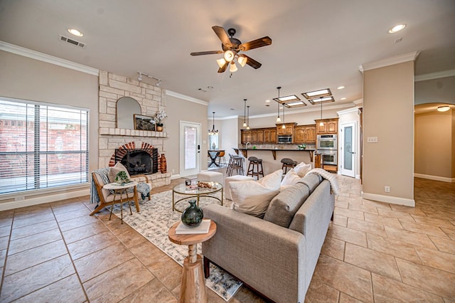 living room featuring ceiling fan, a stone fireplace, and ornamental molding