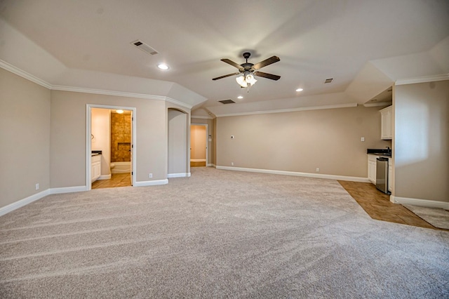 unfurnished living room with ceiling fan, vaulted ceiling, crown molding, and light colored carpet