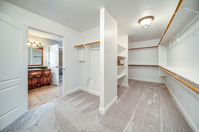 walk in closet featuring sink and light colored carpet