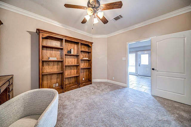 sitting room with ceiling fan, crown molding, and carpet