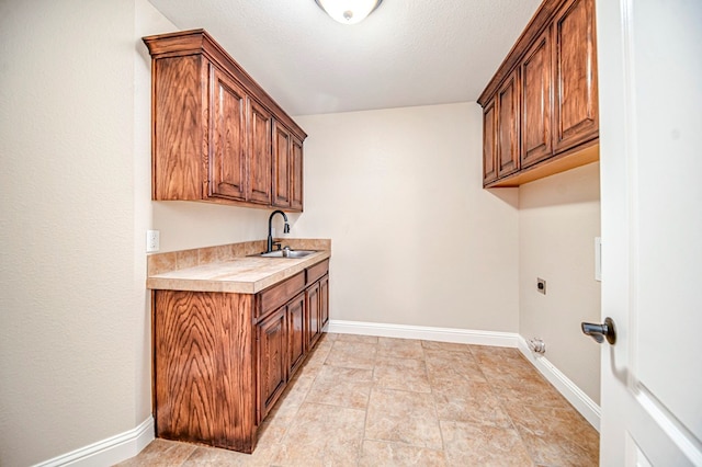 clothes washing area with sink, cabinets, hookup for an electric dryer, and a textured ceiling