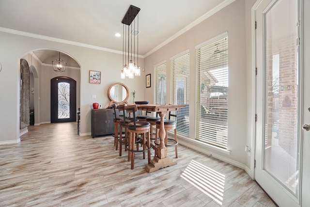 dining area with light hardwood / wood-style flooring, crown molding, and an inviting chandelier