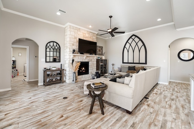 living room featuring a fireplace, light hardwood / wood-style floors, ceiling fan, and crown molding