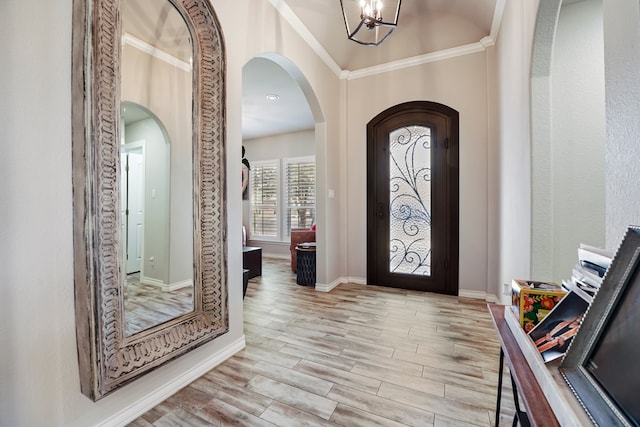 foyer entrance featuring a chandelier, light hardwood / wood-style flooring, and crown molding