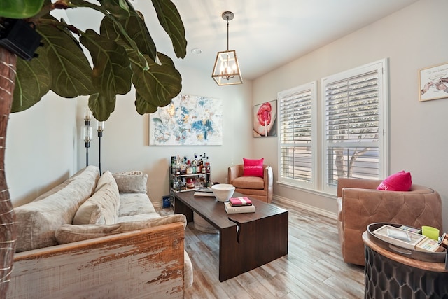 living room with light hardwood / wood-style flooring, a notable chandelier, and a wealth of natural light