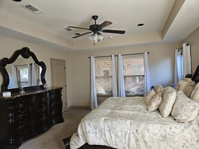 carpeted bedroom featuring a raised ceiling and ceiling fan