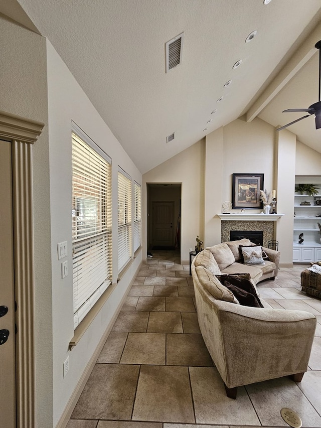 living room with vaulted ceiling with beams, ceiling fan, and a textured ceiling