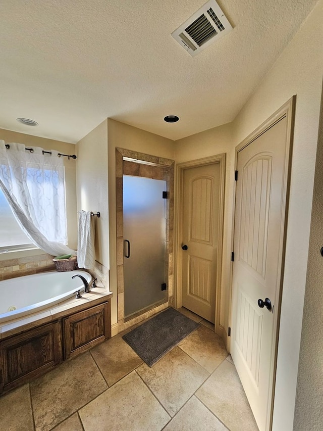 bathroom featuring tile patterned flooring, shower with separate bathtub, and a textured ceiling