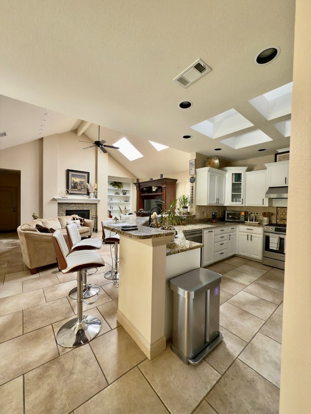 kitchen featuring white cabinetry, kitchen peninsula, dark stone counters, a breakfast bar, and appliances with stainless steel finishes