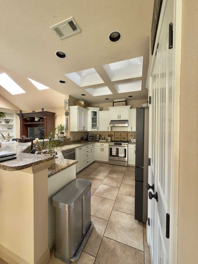 kitchen with kitchen peninsula, a kitchen breakfast bar, stainless steel appliances, sink, and white cabinetry