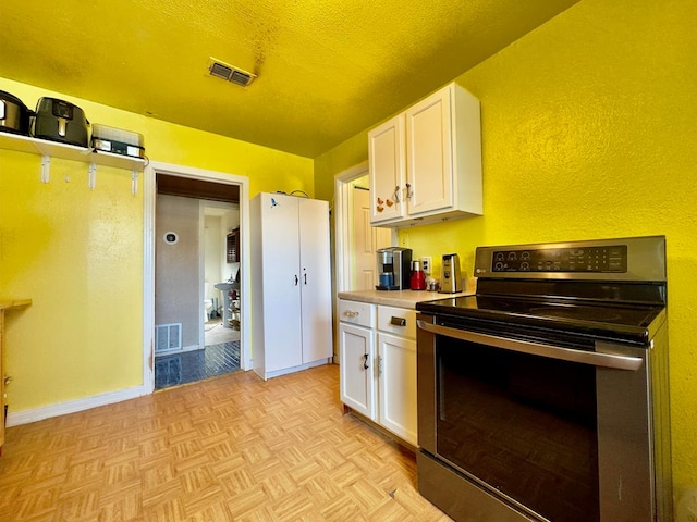 kitchen featuring white cabinets, light parquet floors, a textured ceiling, and black electric range oven