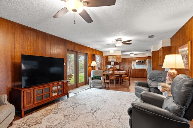 living room featuring wood walls, light hardwood / wood-style floors, and a textured ceiling