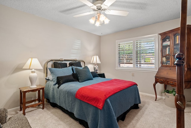 bedroom with a textured ceiling, ceiling fan, and light carpet