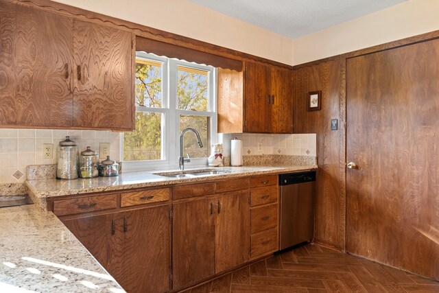 kitchen featuring dishwasher, dark parquet flooring, sink, light stone countertops, and a textured ceiling