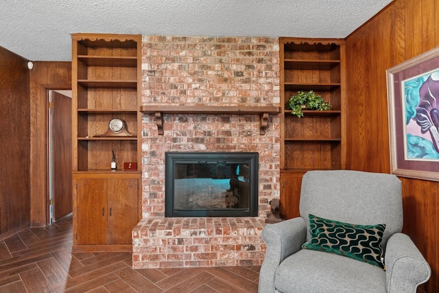 living area featuring a brick fireplace, wood walls, a textured ceiling, and parquet flooring