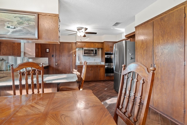 dining area featuring ceiling fan and a textured ceiling