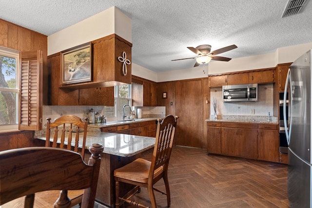 kitchen with dark parquet flooring, stainless steel appliances, a wealth of natural light, and sink