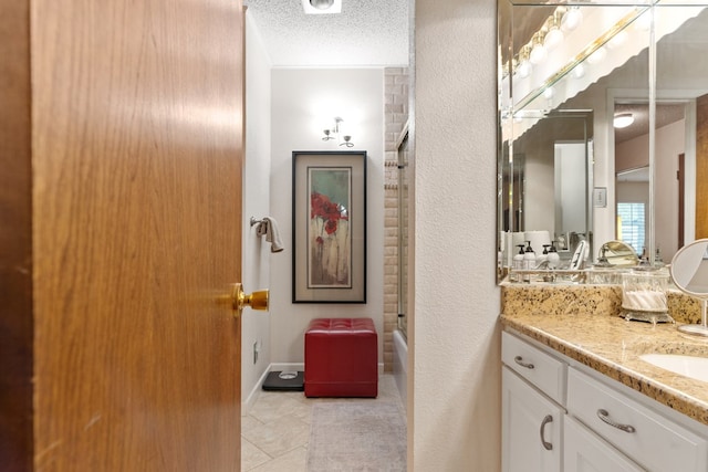 bathroom with tile patterned floors, vanity, combined bath / shower with glass door, and a textured ceiling