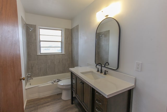 full bathroom with tiled shower / bath combo, vanity, hardwood / wood-style flooring, and toilet