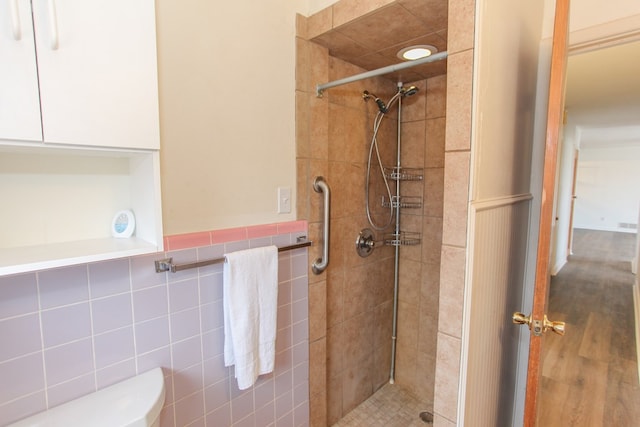 bathroom with tiled shower, tile walls, and toilet