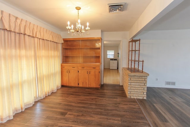 interior space featuring an inviting chandelier, dark hardwood / wood-style flooring, and washer / clothes dryer