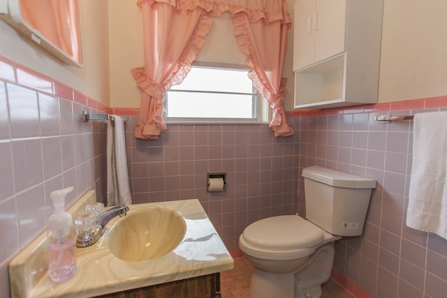 bathroom featuring vanity, toilet, and tile walls