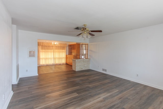 unfurnished living room featuring ceiling fan with notable chandelier and dark hardwood / wood-style floors