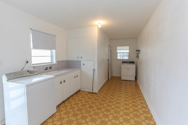 clothes washing area featuring sink, washer / dryer, plenty of natural light, and cabinets