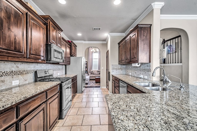 5700 San Miguel Ave, Midland, TX 79705 - kitchen featuring appliances with stainless steel finishes, arched walkways, a sink, light stone counters, and dark brown cabinets
