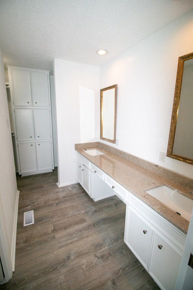 bathroom featuring hardwood / wood-style floors, vanity, and a textured ceiling