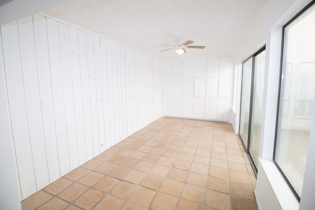 spare room featuring wood walls, ceiling fan, and a textured ceiling