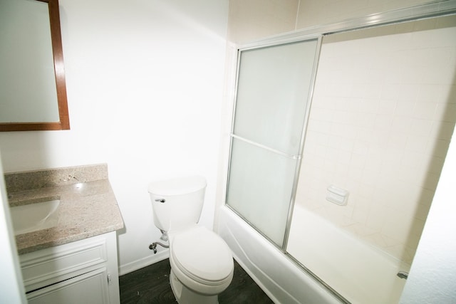 full bathroom with shower / bath combination with glass door, hardwood / wood-style floors, vanity, and toilet