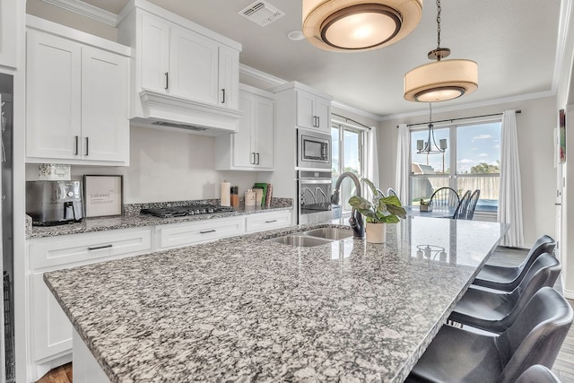 4107 Connally St, Big Spring, TX 79720 - kitchen featuring stainless steel appliances, ornamental molding, white cabinetry, a center island with sink, and custom exhaust hood