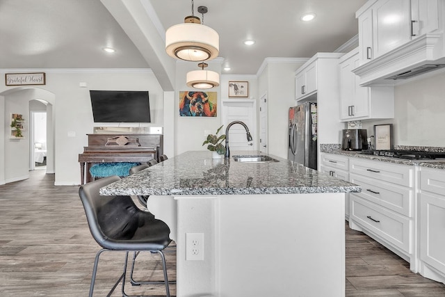 4107 Connally St, Big Spring, TX 79720 - kitchen featuring appliances with stainless steel finishes, ornamental molding, arched walkways, dark stone countertops, and white cabinets