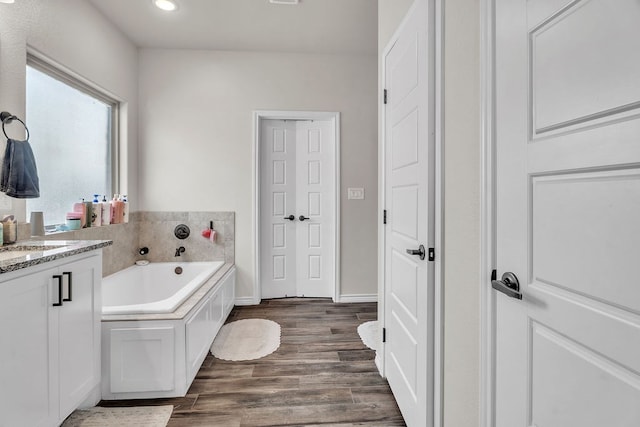 4107 Connally St, Big Spring, TX 79720 - full bathroom featuring a garden tub, vanity, wood finished floors, and recessed lighting