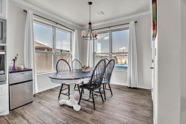 4107 Connally St, Big Spring, TX 79720 - dining area featuring ornamental molding, plenty of natural light, wood finished floors, and a chandelier