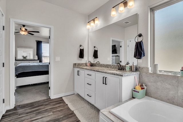 4107 Connally St, Big Spring, TX 79720 - full bathroom featuring wood finished floors, double vanity, ensuite bathroom, a bath, and a ceiling fan