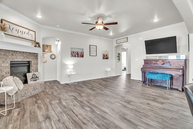 4107 Connally St, Big Spring, TX 79720 - living area with arched walkways, ceiling fan, a fireplace, wood finished floors, and ornamental molding