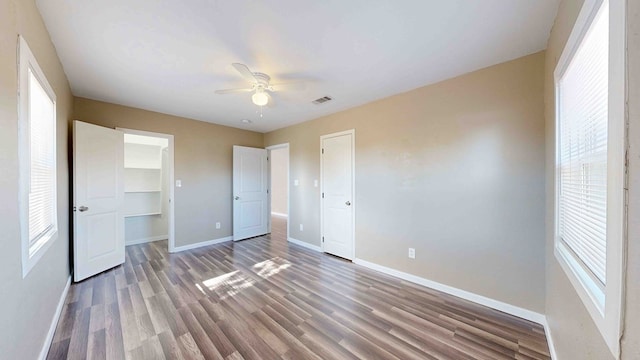 unfurnished bedroom featuring multiple windows, ceiling fan, a closet, and hardwood / wood-style flooring