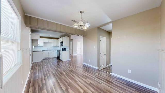 kitchen featuring hanging light fixtures, an inviting chandelier, black electric range, white cabinets, and hardwood / wood-style flooring