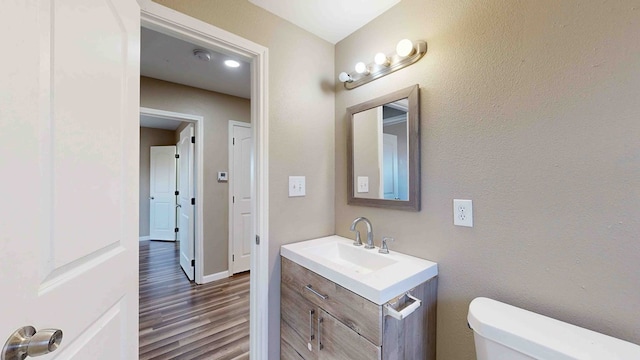 bathroom featuring wood-type flooring, vanity, and toilet