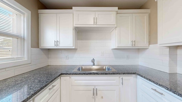 kitchen featuring white cabinets, backsplash, a wealth of natural light, and sink