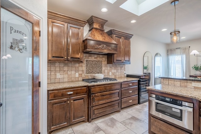 5607 Camino Reale, Midland, TX 79707 - kitchen featuring a skylight, premium range hood, stainless steel appliances, decorative backsplash, and recessed lighting